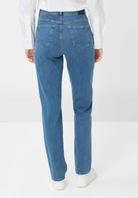 Hellblaue Jeans im gerade geschnittenen Stil mit zwei Gesäßtaschen und einem speziellen Bunddesign, kombiniert mit weißen Sneakern.