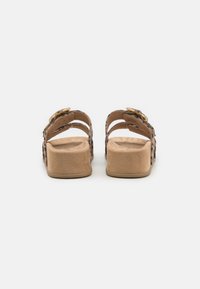 Brune suedè sklisandaler med to justerbare stropper, en lav plattformsåle og dyreprintmønster på stroppene.