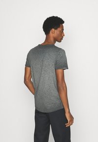 Camiseta de manga corta y cuello redondo, hecha de tela gris texturizada; presenta un sutil patrón jaspeado y un corte relajado.