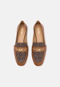 Ett par bruna läder loafers från Michael Kors med monogramtyginsatser och guldfärgade MK-logotypdetaljer på toppen, visade från ovan.