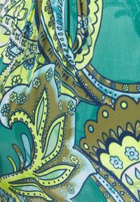 Geweven stof met patronen in te groen en turquoise bloemenontwerpen, met ingewikkelde details en contrasterende gevlochten lijnen in donkerblauw en bruin.