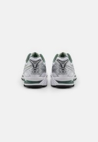 Running shoes with a white mesh upper, green accents, and silver detailing. Cushioned sole with textured grip. Features logo on heels.