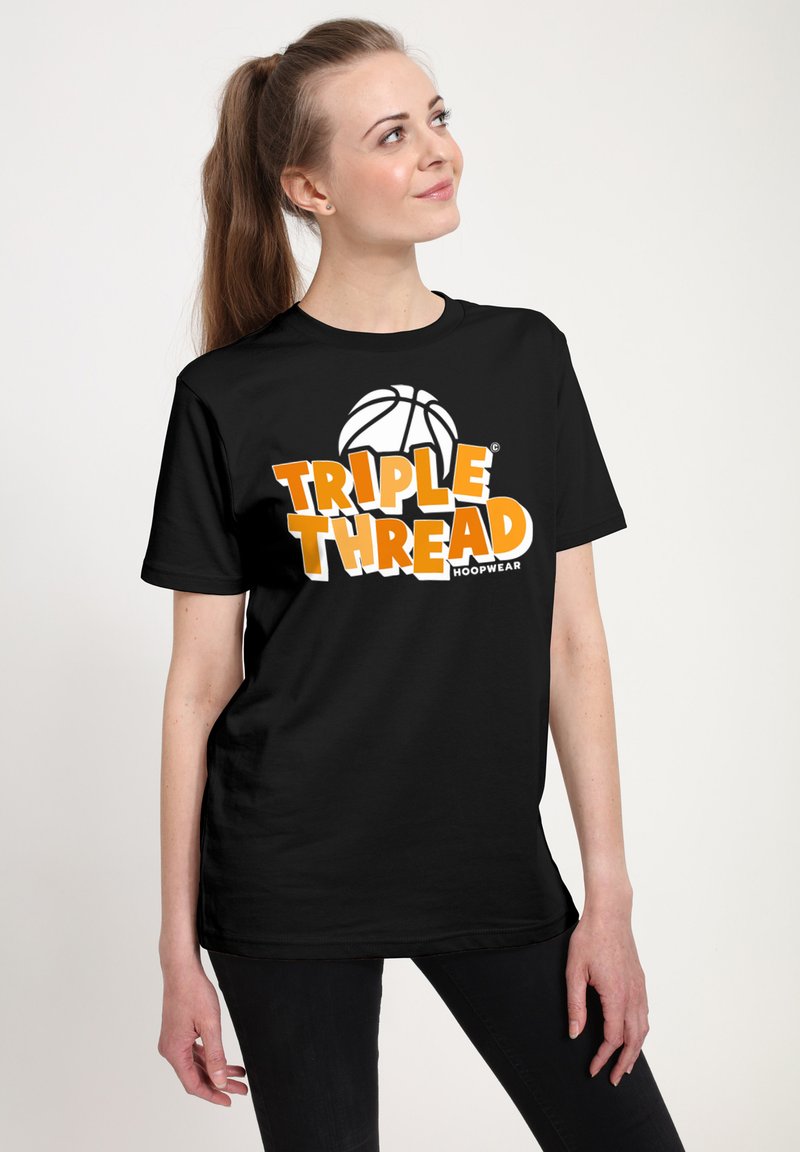 Woman wearing black "TRIPLE THREAD" T-shirt with basketball graphic, standing against plain light background, looking to the side.