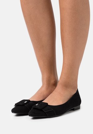 Les ballerines en cuir suédé noir présentent un bout arrondi, un accent de nœud texturé sur le devant, et un petit talon carré. Finition lisse avec des détails de couture subtils.