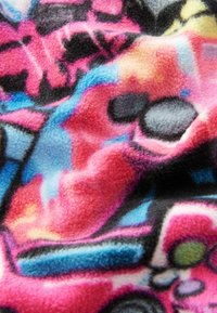 Farbenfrohe Fleece-Decke mit einer Mischung aus leuchtendem Pink, Blau und schwarzen abstrakten Mustern sowie einer weichen, strukturierten Oberfläche.