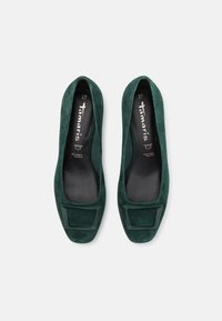 Ballerines en daim vert avec un bout carré et une semelle plate. Texture lisse et design minimaliste, avec un accent subtil sur la zone des orteils.