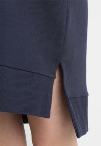 Vestido de suéter de algodón azul marino con aberturas laterales, dobladillo acanalado y textura suave. Enfocado en la simplicidad y la comodidad en el diseño.