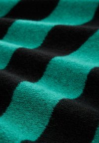 Gewebter Stoff mit abwechselnden Streifen in Türkis und Schwarz. Die Textur ist weich und fuzzy, mit sichtbaren Fasern und einem diagonalen Muster.