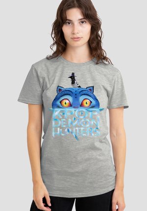 Gray t-shirt featuring a blue cat's face with large yellow eyes, a black bird wearing a top hat, and blue text reading "KPOP DEMON HUNTERS."