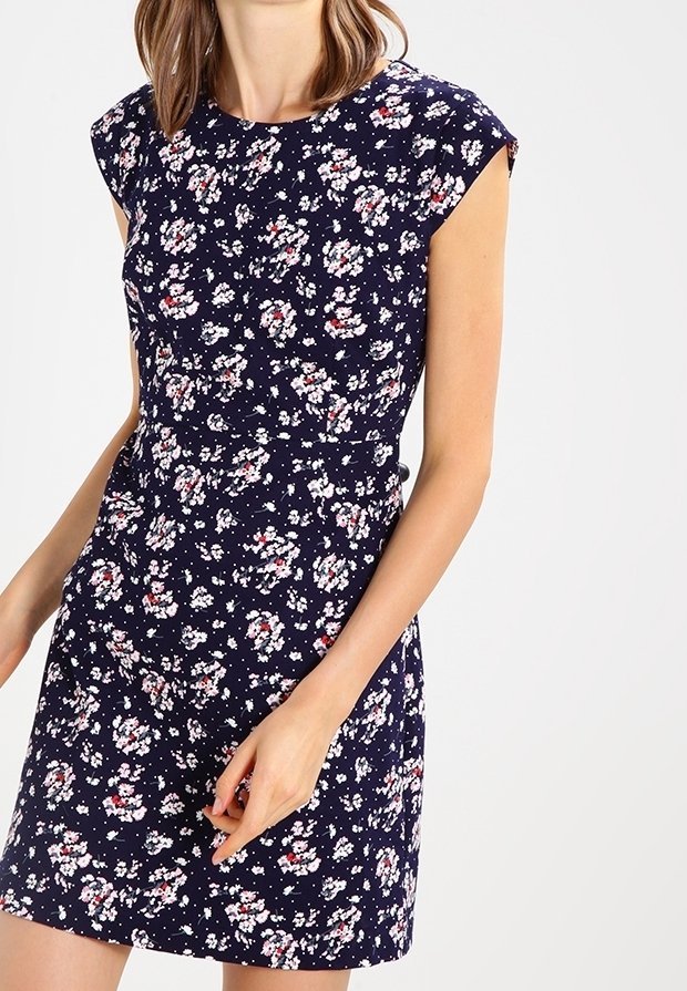 Navy floral dress with cap sleeves, featuring a fitted waist and scattered white and red floral patterns. Soft fabric with slight texture.