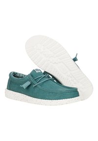 Scarpe in tessuto turchese con superficie testurizzata, suola in gomma bianca maculata e fodera a motivo. Presentano un laccio frontale con un toggle.