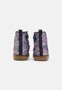 Ankelstøvler med mørkeblå ruskindskant, dækket af multicolorer glimmer, med en tekstureret overflade og en flad brun sål.