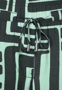 Czarno-miętowe szorty w wzory z elastycznym paskiem, z metalicznymi akcentami i miękką teksturą materiału.