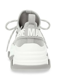 Scarpa sportiva grigia con tomaia in mesh testurizzato, lacci elastici, suola bianca spessa e testo "THE MADE" sulla cinghia del tallone.