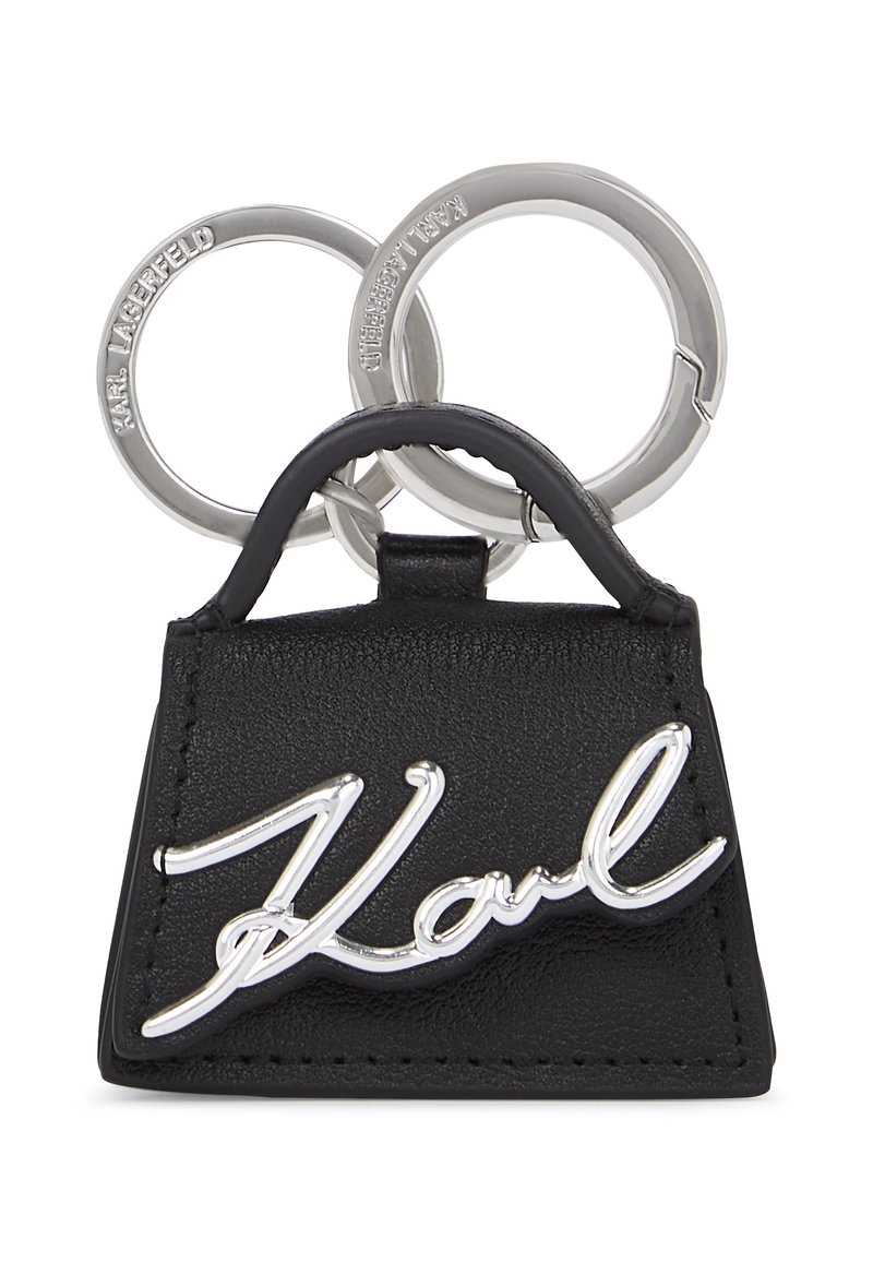 Zwarte leren sleutelhanger in de vorm van een handtas, met een zilveren "Karl" logo en twee zilveren sleuterringen eraan bevestigd. Gestructureerd oppervlak met stiksel.