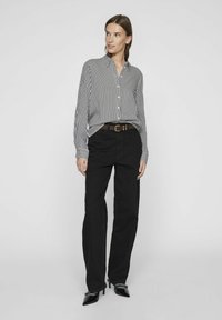 Black and white striped button-up shirt with a collar, paired with high-waisted black jeans and shiny black high-heeled shoes. Brown belt.