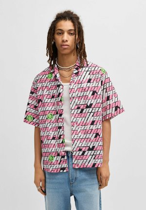 Short-sleeve button-up shirt in pink, black, and white. Features bold text patterns and green smiley accents on lightweight fabric.