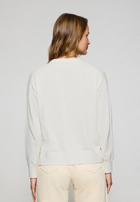 Helle Cream Sweatshirt mit langen Ärmeln, rundem Halsausschnitt, gerippten Bündchen und Saum. Weicher Stoff mit lockerer Passform. Keine sichtbaren Muster.