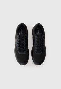 Black athletic shoes featuring a smooth synthetic upper, round laces, textured toe cap, and a small logo detail on the side.