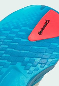 Modrá podešev obuvi s texturovaným geometrickým vzorem a červenou částí s gripem Continental.