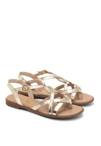 Gouden metalen sandalen met kruislings gespen, platte zolen en een gesp-sluiting. Zachte tan voetbed met minimale voering en een gladde textuur.
