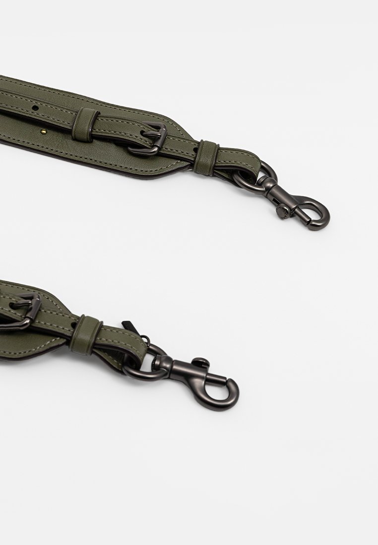 Zielono-oliwkowy pasek ze sztucznej skóry z regulowanym zapięciem, wyposażony w czarne metalowe klipsy na obu końcach do mocowania. Gładka tekstura, minimalistyczny design.