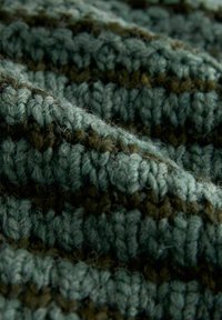 Knitted fabric in varying shades of green and brown, featuring a textured pattern with prominent yarn details and softness.