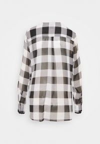 Chemise à longue manche à carreaux noir et blanc avec un col droit, vue de dos sur un fond blanc uni.