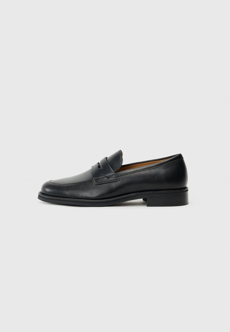 Black leather loafers with a rounded toe, featuring a front strap detail and a low, solid heel. Smooth texture and sleek design.