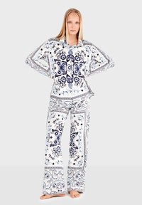 Weißes Schlafanzugset mit marineblauen floralem und Paisleymuster. Es besteht aus einem locker sitzenden Hemd mit Kragen und passenden, weiten Hosen.