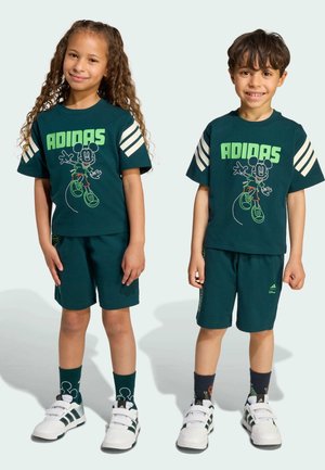 Green cotton t-shirts with white stripes, featuring a Mickey Mouse graphic. Matching shorts and sneakers with green accents complete the outfits.