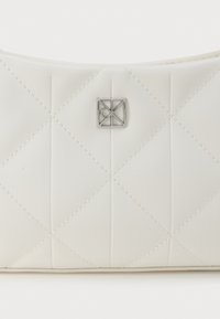 Fehér steppelt kézitáska sima anyagból, gyémántmintázattal, ezüst logóval és hozzáillő varrással.