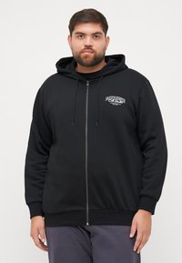 Crna zip-up dukserica od mekog materijala s kapuljačom na vezanje i malim logotipom na prsima, s rebrastim manšetama i donjim rubom.