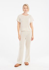 Set da loungewear di colore crema in maglia, composto da una maglietta a maniche corte con tasca e pantaloni a gamba larga, caratterizzato da un motivo a diamante testurizzato.