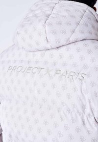 Giacca a vento bianca con design trapuntato, caratterizzata da un motivo a logo grigio chiaro ripetuto e "PROJECT X PARIS" ricamato sulla schiena.