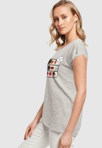 Grå T-shirt lavet af blød bomuld, med grafisk motiv af tre øjne og en taleboble. Rund hals og korte ærmer med en afslappet pasform.