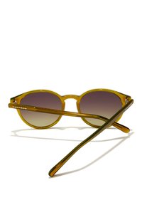 Ringikujulised päikeseprillid läbipaistva oliivrohelise raami, gradientsete pruunide läätsede ja roheliste detailidega sangadega, millel on brändinimi "HAWKERS".