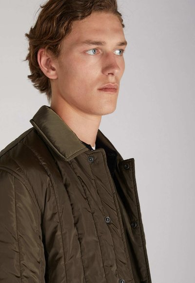 Veste matelassée en vert olive foncé avec un col contrastant. Présente des boutons-pression et une surface texturée.