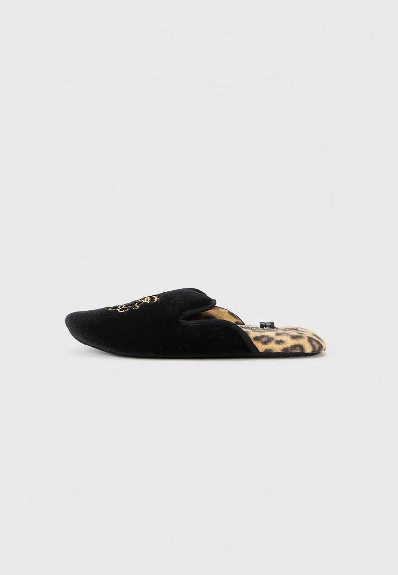Pantuflas de terciopelo negro con un diseño bordado en la parte superior, con la parte trasera abierta y un forro de leopardo. Suela plana y forma de punta.
