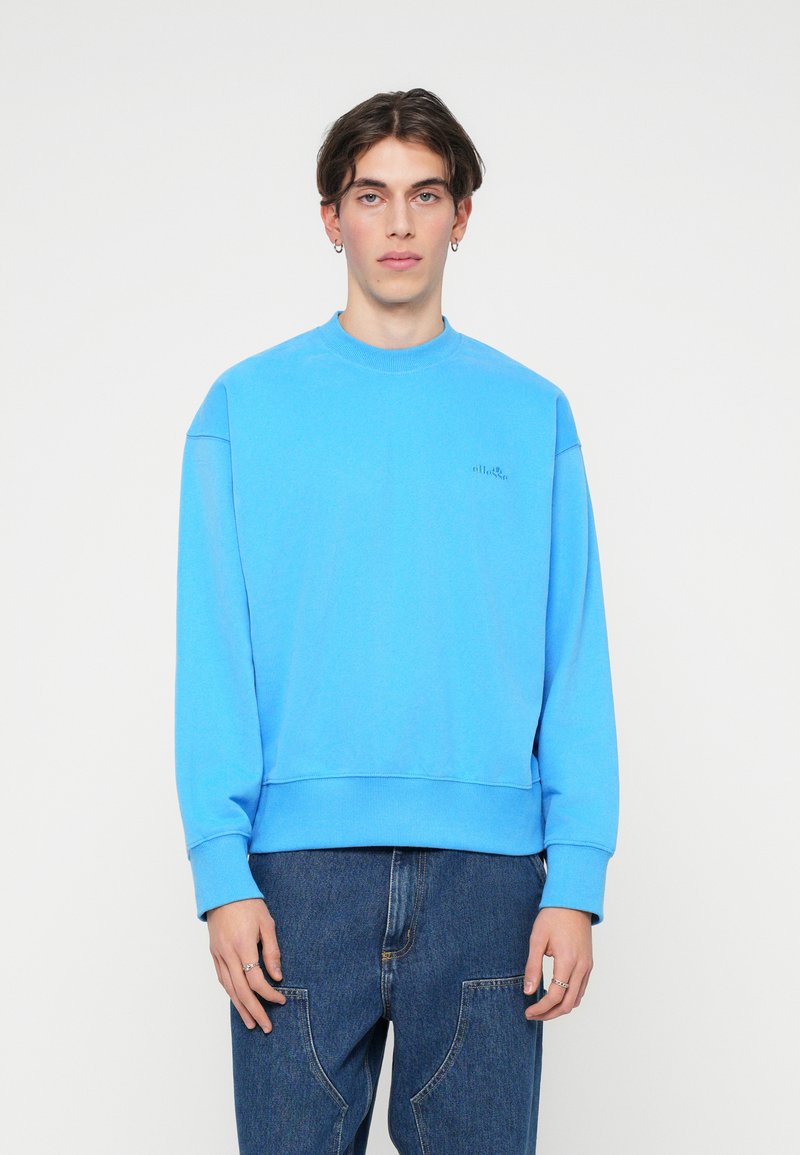 Svetlo modrý crew neck sveter vyrobený z mäkkého materiálu, s rebrovanými manžetami a lemom, so malým logom na hrudi.