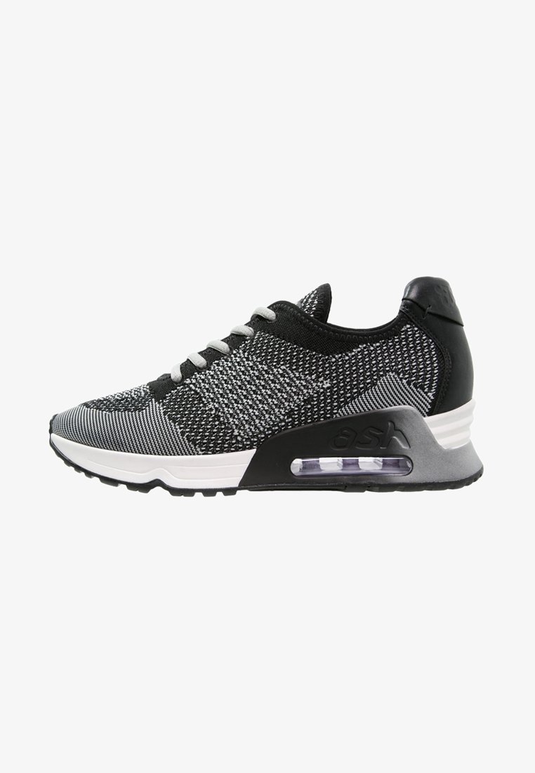 Black and white knit athletic shoes with a textured upper, contrasting heel, and visible air cushioning in the sole.