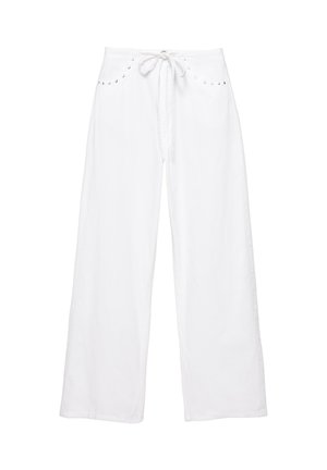 Biele široké nohavice so šnúrkou v páse a malými striebornými cvočkami pozdĺž okrajov predných vreciek, jednofarebné pozadie.