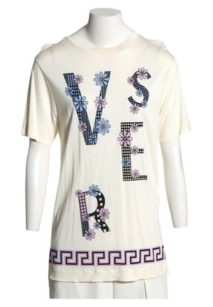 Camisa blanca de manga corta con grandes letras estilizadas que forman "VERSER", decorada con flores en tonos pastel y un borde con patrón geométrico en el dobladillo.
