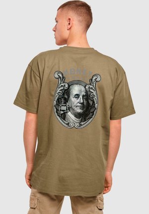 Olívazöld pamut póló, nagy fekete-fehér Benjamin Franklin grafikával, díszítő elemekkel és "A PÉNZ SOHA NEM HAZUDIK" szöveggel.