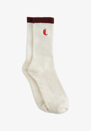 Calzini bianchi a coste con polsino bordeaux, caratterizzati da un piccolo peperoncino rosso ricamato sul lato. Tessuto morbido, design casual.