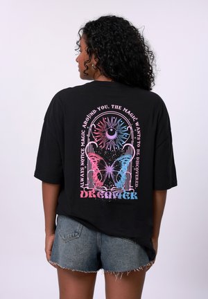 Black oversized t-shirt featuring a colorful butterfly and sun graphic on the back, with white text and a relaxed fit design.