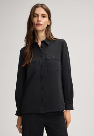 Zwarte shirt met lange mouwen, knoopsluiting aan de voorkant, twee borstzakken, zachte textuur, rechte snit en gedetailleerde stiksels.