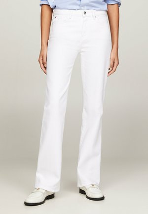 Jeans flare bianchi in misto cotone, con vita con bottoni, passanti per cintura e una texture liscia. Abbinati a una camicia a righe leggera.