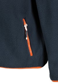 Tumman merensininen fleecetakki oranssilla vetoketjullisella taskulla, jossa on teksturoitu kangas ja eroava oranssi vuori helman ympäri.