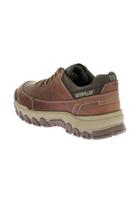 Zapato de cuero marrón con una suela de goma color tan resistente, que presenta un upper texturizado, acentos cosidos y una lengua de malla con marca para mayor transpirabilidad.